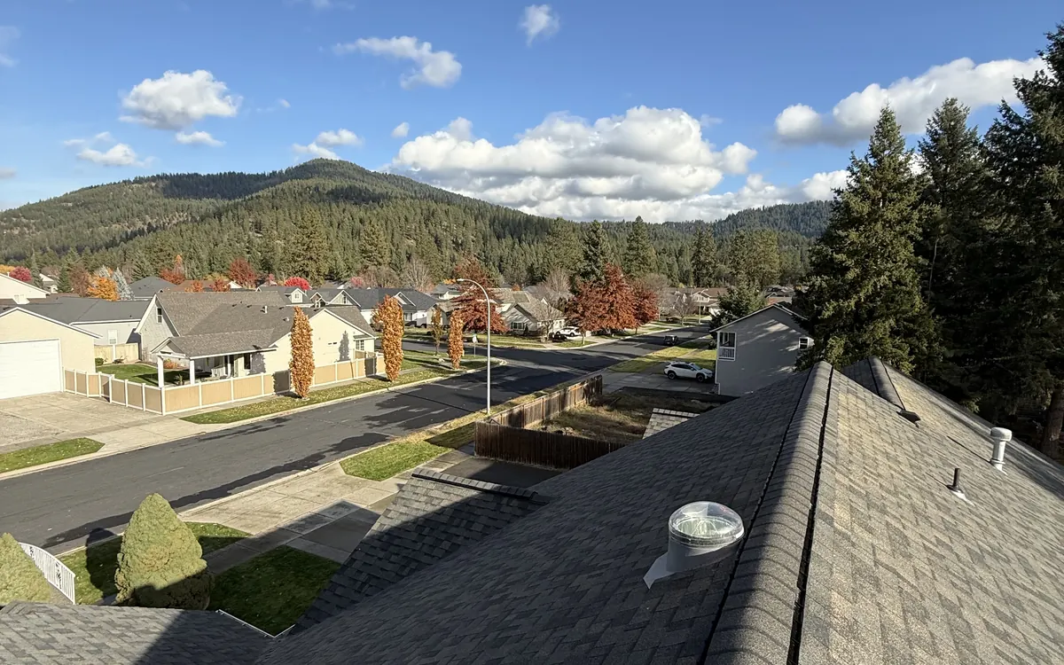 Shingle roof overlooking a neighborhood and forested hills, photographed by Lakeview Roofing