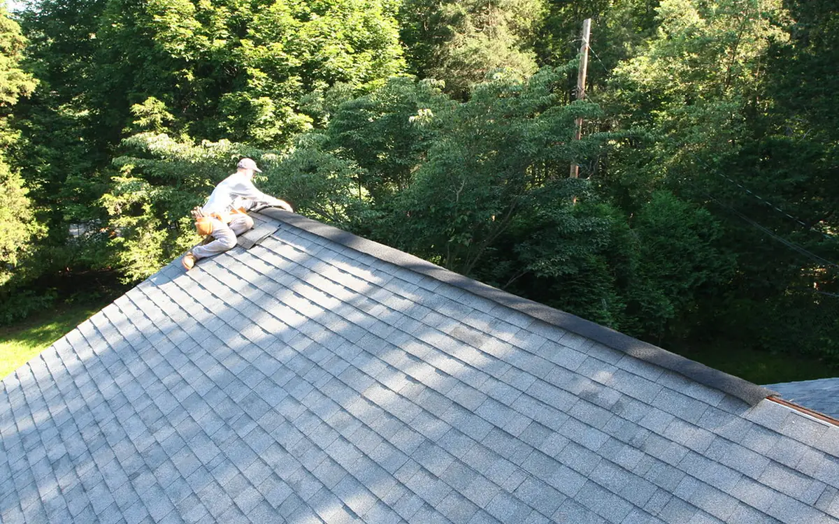 Roofer installing a ridge vent along the peak of an asphalt shingle roof