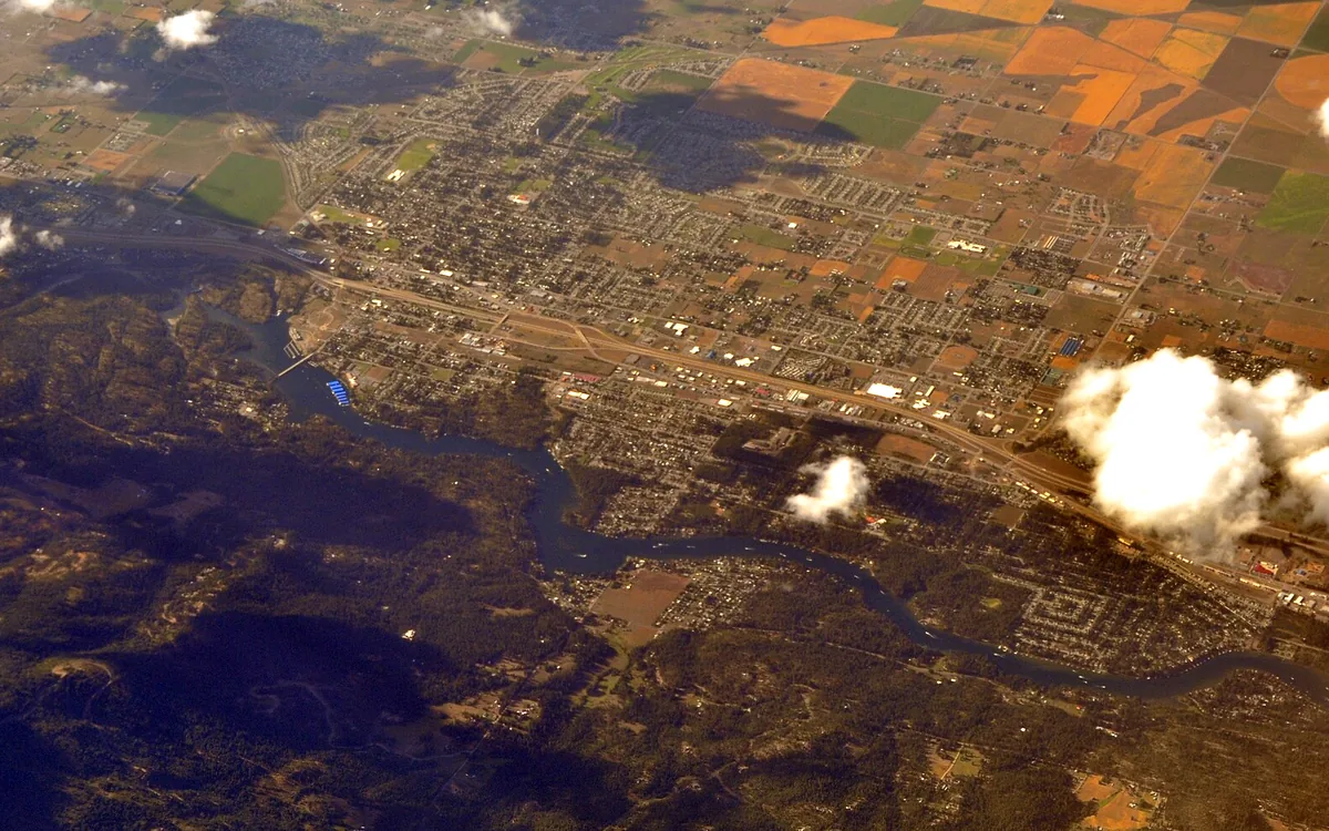 Aerial view of Post Falls, Idaho, with neighborhoods, Interstate 90, and the Spokane River winding along the south side of town
