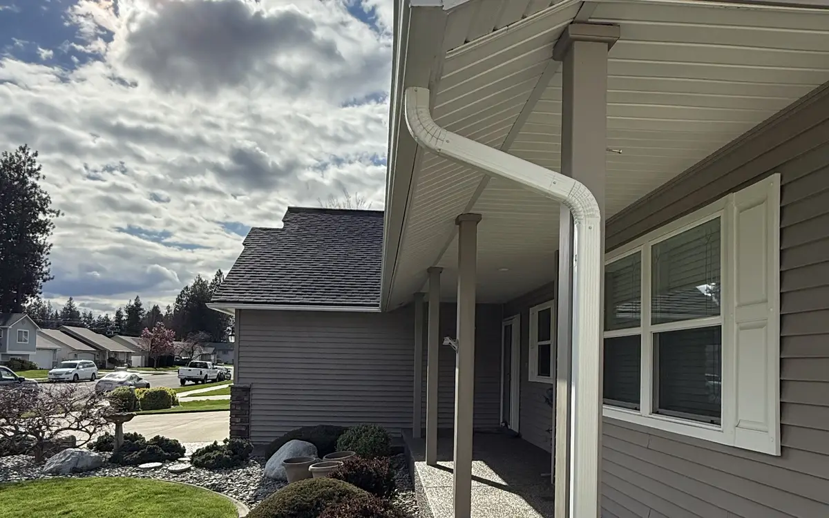 White downspout running from the eave down a porch post on a gray-sided house